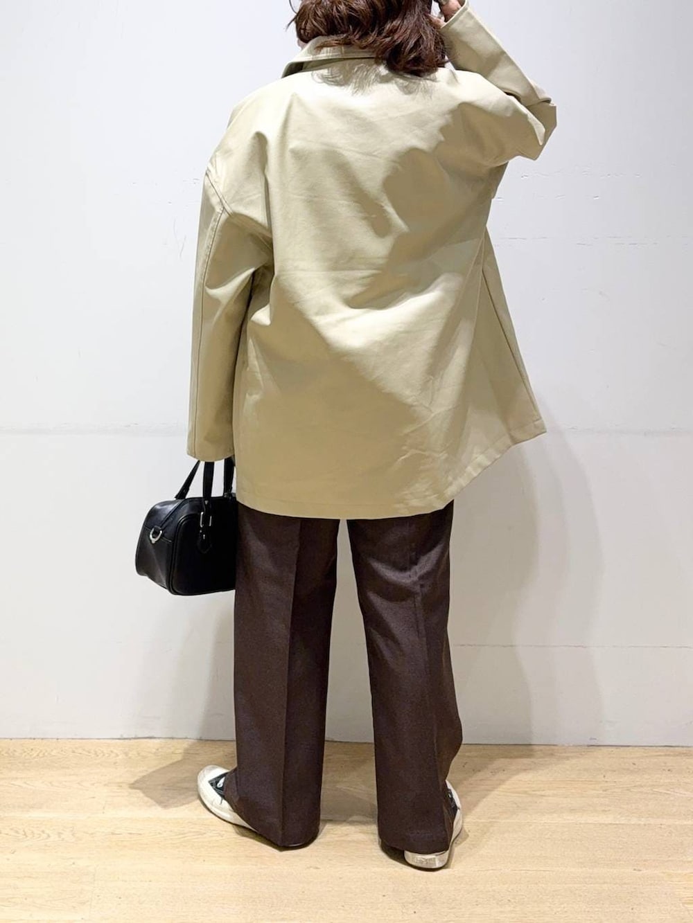 ベージュ系のステンカラーコート、ブラウン系のスラックス、グリーン系のシャツ/ブラウスを着用したレディースの秋コーディネートの4枚目の写真