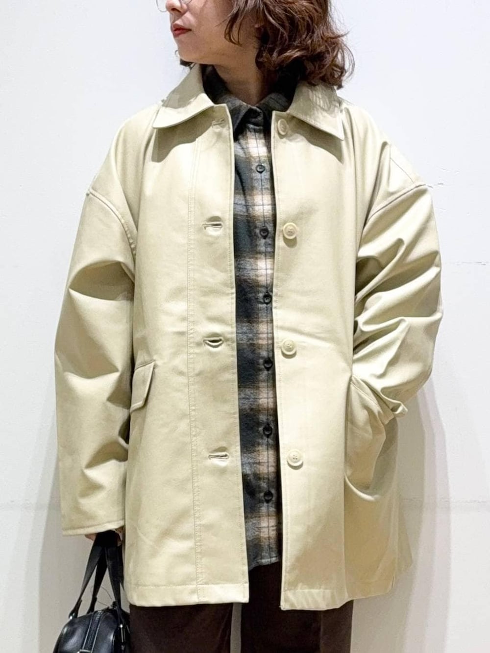 ベージュ系のステンカラーコート、ブラウン系のスラックス、グリーン系のシャツ/ブラウスを着用したレディースの秋コーディネートの6枚目の写真