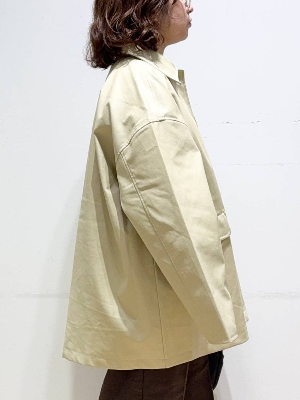 ベージュ系のステンカラーコート、ブラウン系のスラックス、グリーン系のシャツ/ブラウスを着用したレディースの秋コーディネートの7枚目の写真