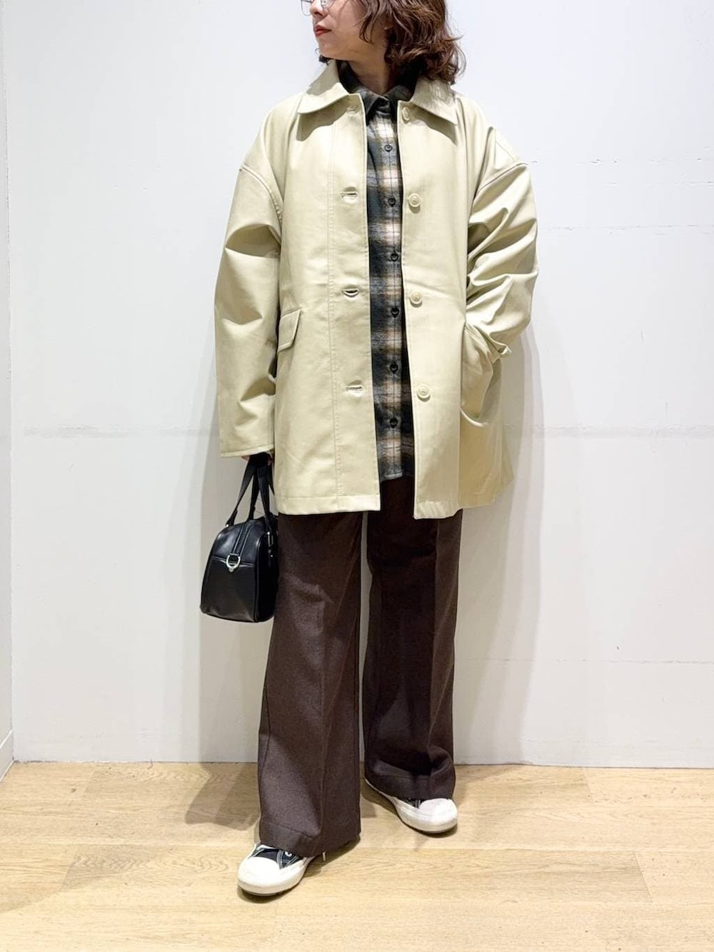 ベージュ系のステンカラーコート、ブラウン系のスラックス、グリーン系のシャツ/ブラウスを着用したレディースの秋コーディネートの2枚目の写真