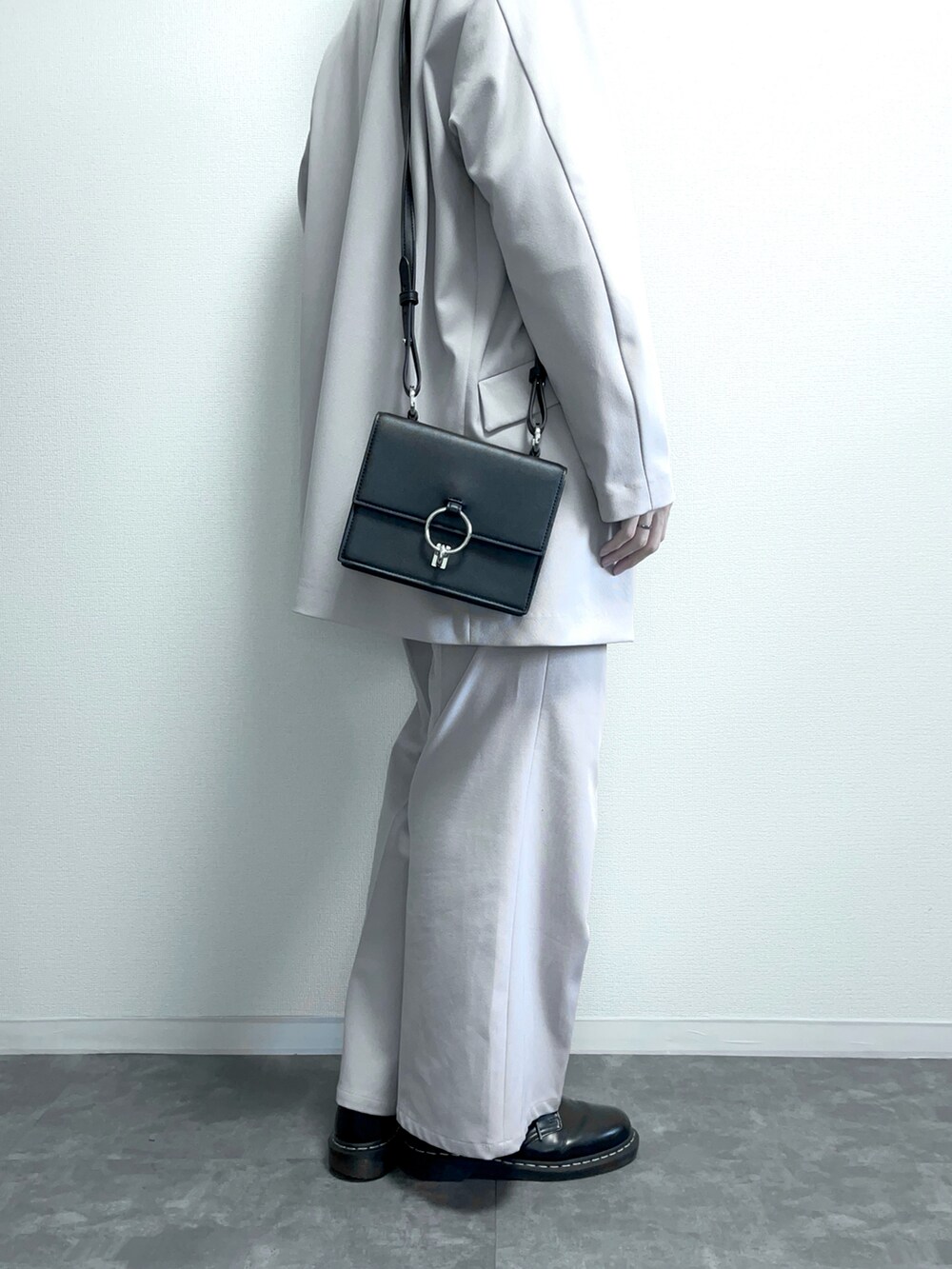 ブラック系のドレスシューズ、グレー系のスラックス、ブラック系のショルダーバッグを着用したメンズの冬コーディネートの2枚目の写真