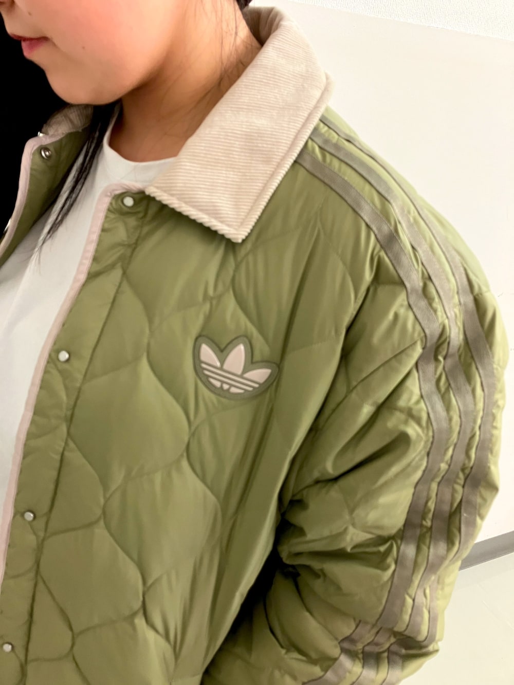 グリーン系のダウンジャケット/コート、イエロー系のスニーカーを着用したレディースの秋コーディネートの3枚目の写真