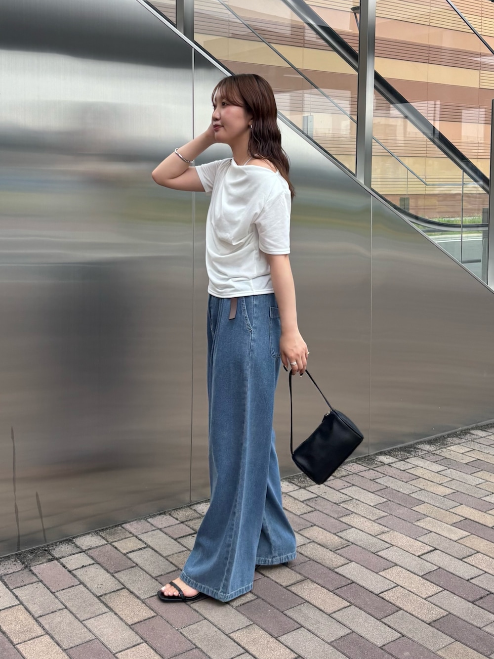 ブルー系のデニムパンツ、ホワイト系のTシャツ/カットソー、ブラック系のハンドバッグを着用したレディースの夏コーディネートの2枚目の写真