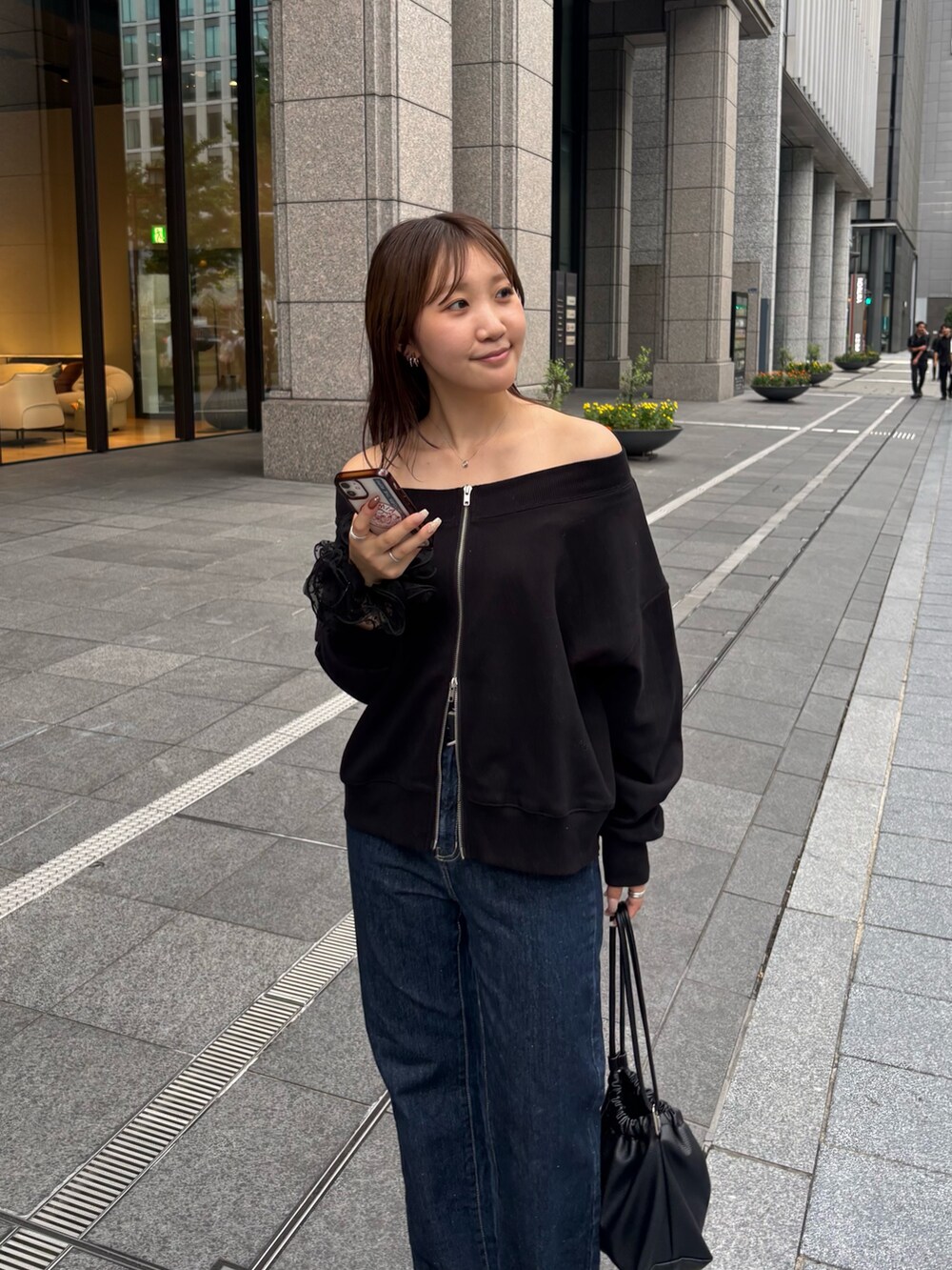 ブラック系のTシャツ/カットソー、ブラック系のショルダーバッグ、ブルー系のデニムパンツを着用したレディースの秋コーディネートの3枚目の写真
