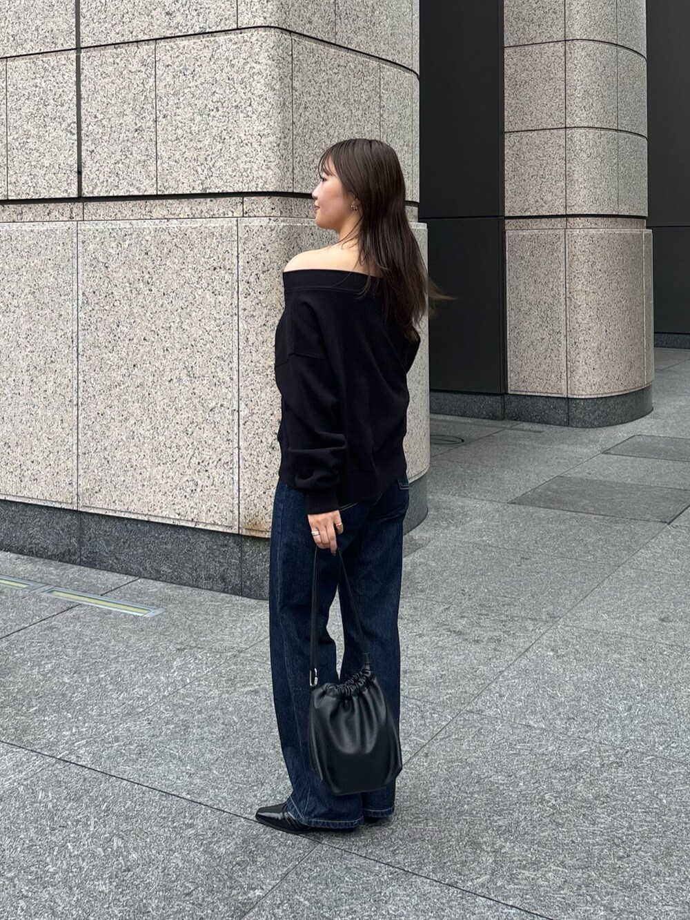 ブラック系のTシャツ/カットソー、ブラック系のショルダーバッグ、ブルー系のデニムパンツを着用したレディースの秋コーディネートの2枚目の写真