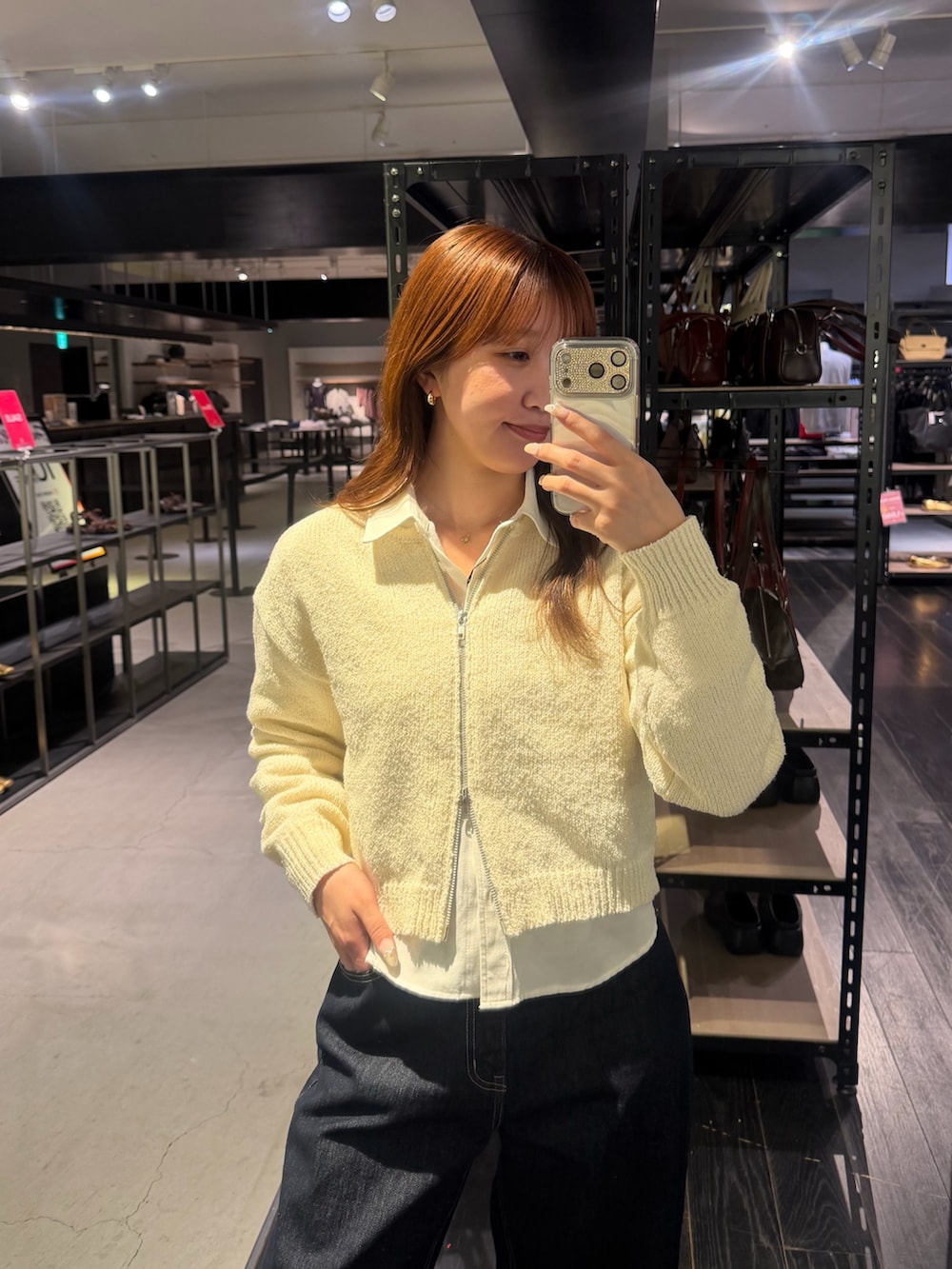 ホワイト系のカーディガン/ボレロ、ホワイト系のシャツ/ブラウス、ブルー系のデニムパンツを着用したレディースの春コーディネートの2枚目の写真