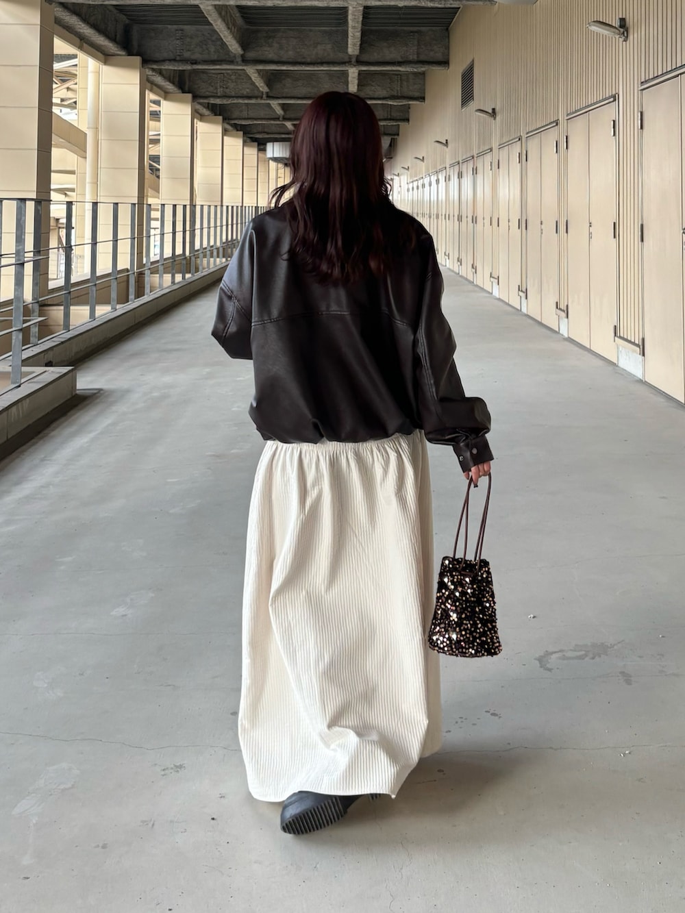 ブラウン系のブルゾン、ホワイト系のスカート、その他のショルダーバッグを着用したレディースの冬コーディネートの3枚目の写真