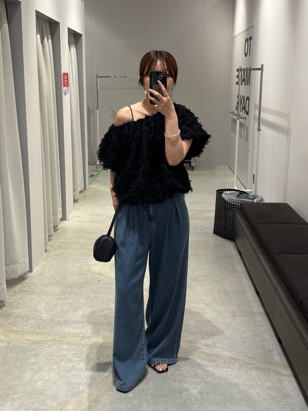 ブルー系のデニムパンツ、ブラック系のその他トップス、ブラック系のハンドバッグを着用したレディースの夏コーディネートの3枚目の写真