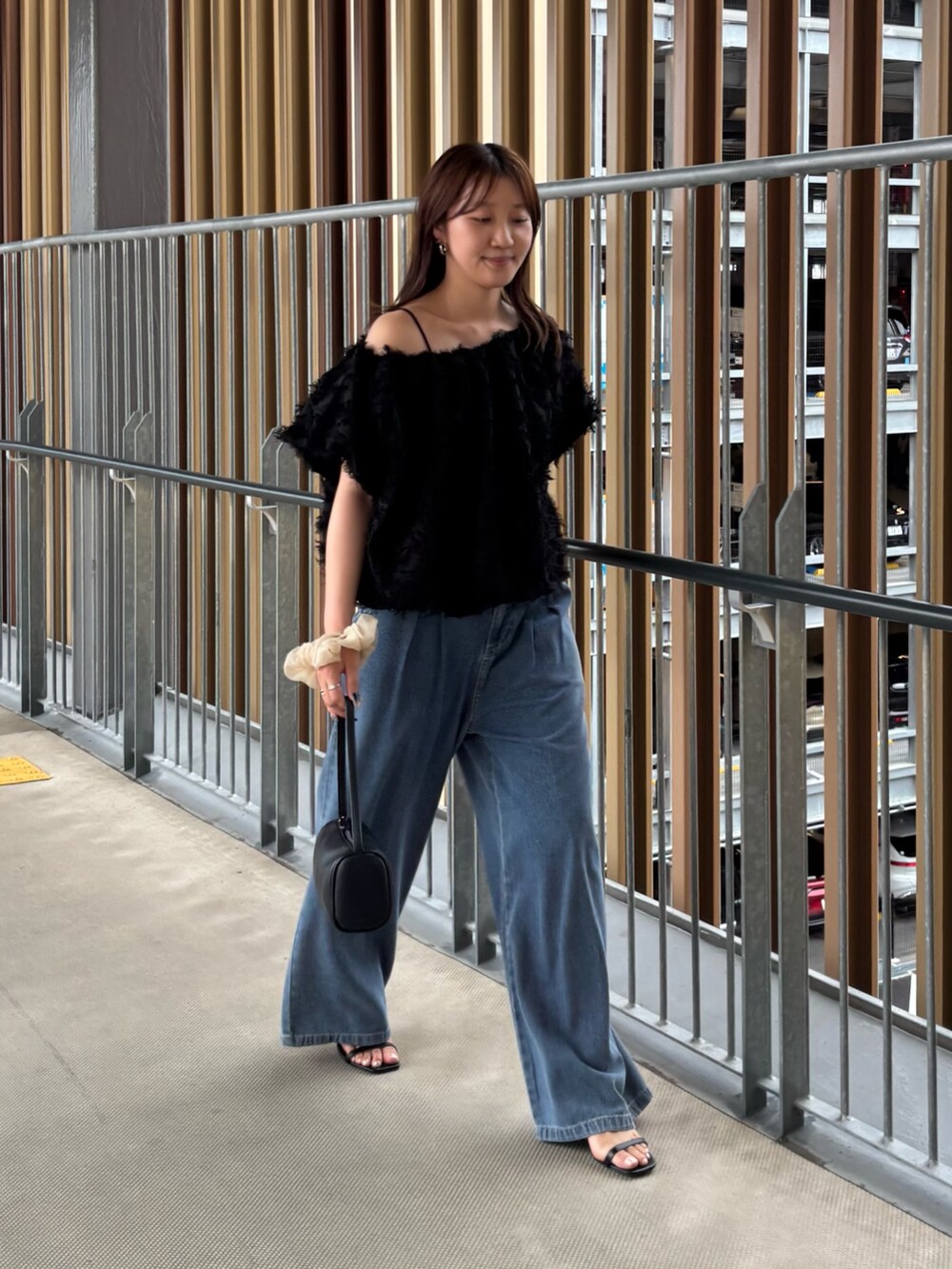 ブルー系のデニムパンツ、ブラック系のその他トップス、ブラック系のハンドバッグを着用したレディースの夏コーディネートの2枚目の写真