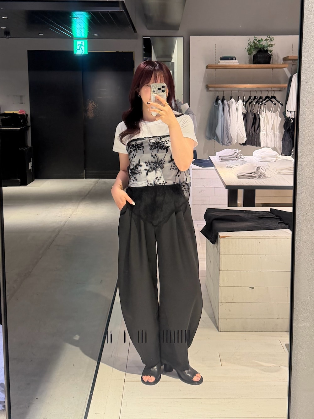 ブラック系のスラックス、ホワイト系のTシャツ/カットソー、ブラック系のサンダルを着用したレディースの夏コーディネートの3枚目の写真