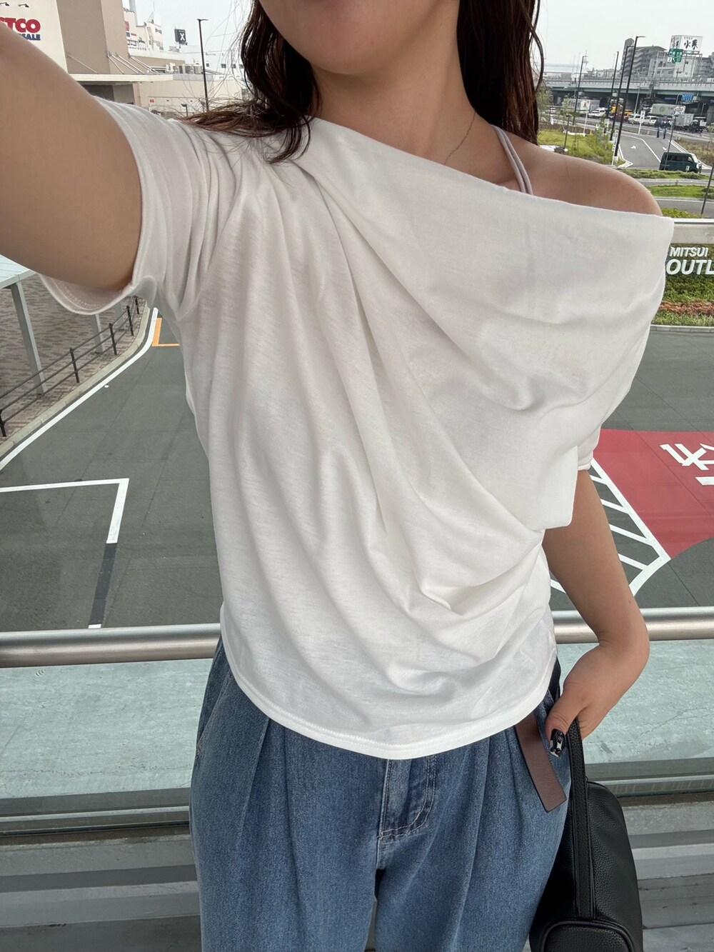 ブルー系のデニムパンツ、ホワイト系のTシャツ/カットソー、ブラック系のハンドバッグを着用したレディースの夏コーディネートの3枚目の写真