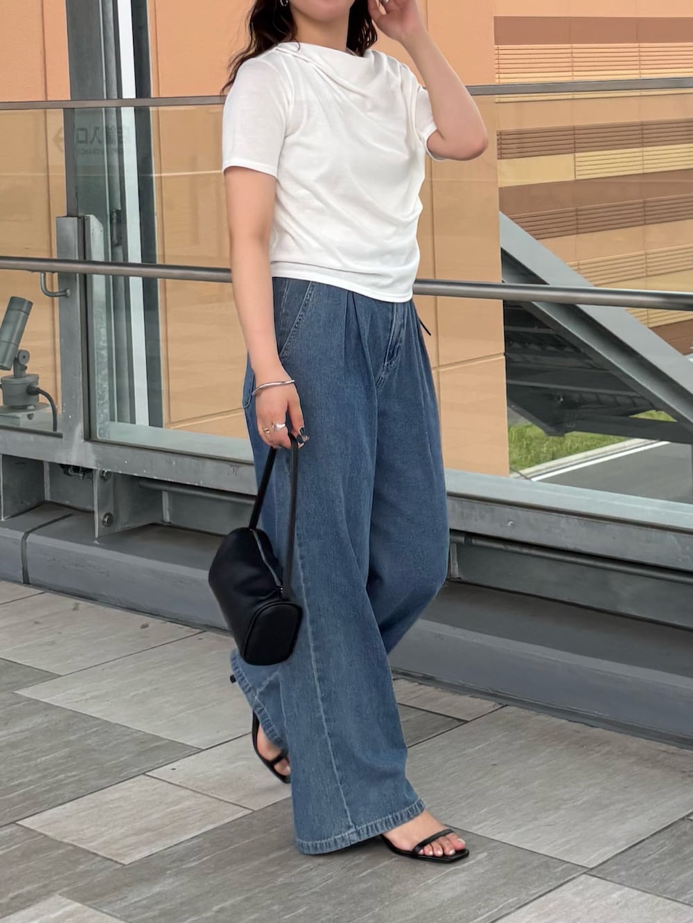 ブルー系のデニムパンツ、ホワイト系のTシャツ/カットソー、ブラック系のハンドバッグを着用したレディースの夏コーディネートの4枚目の写真