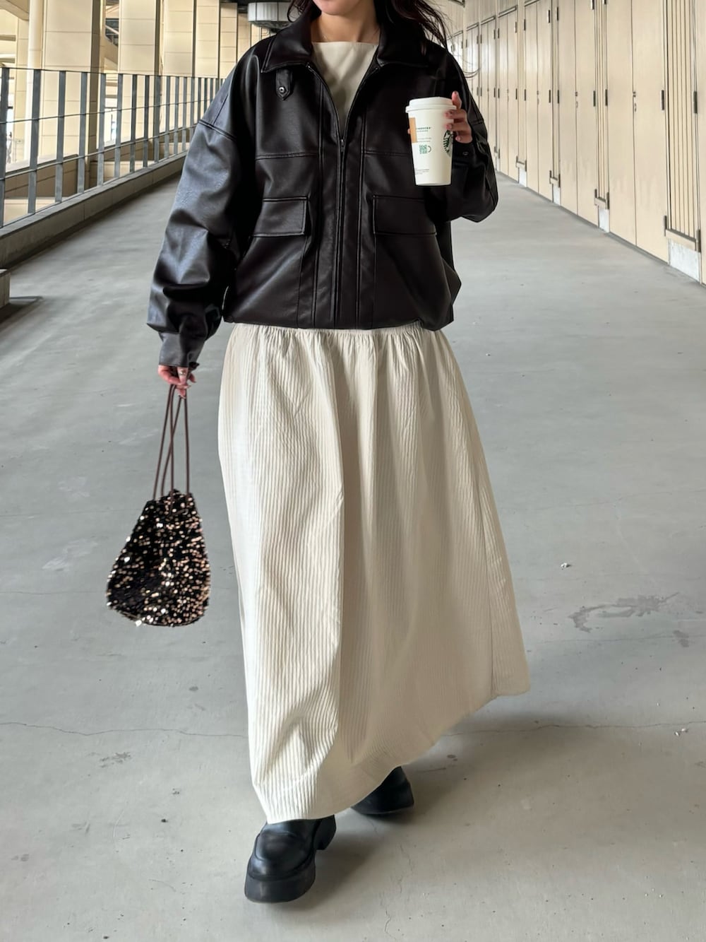 ブラウン系のブルゾン、ホワイト系のスカート、その他のショルダーバッグを着用したレディースの冬コーディネートの2枚目の写真