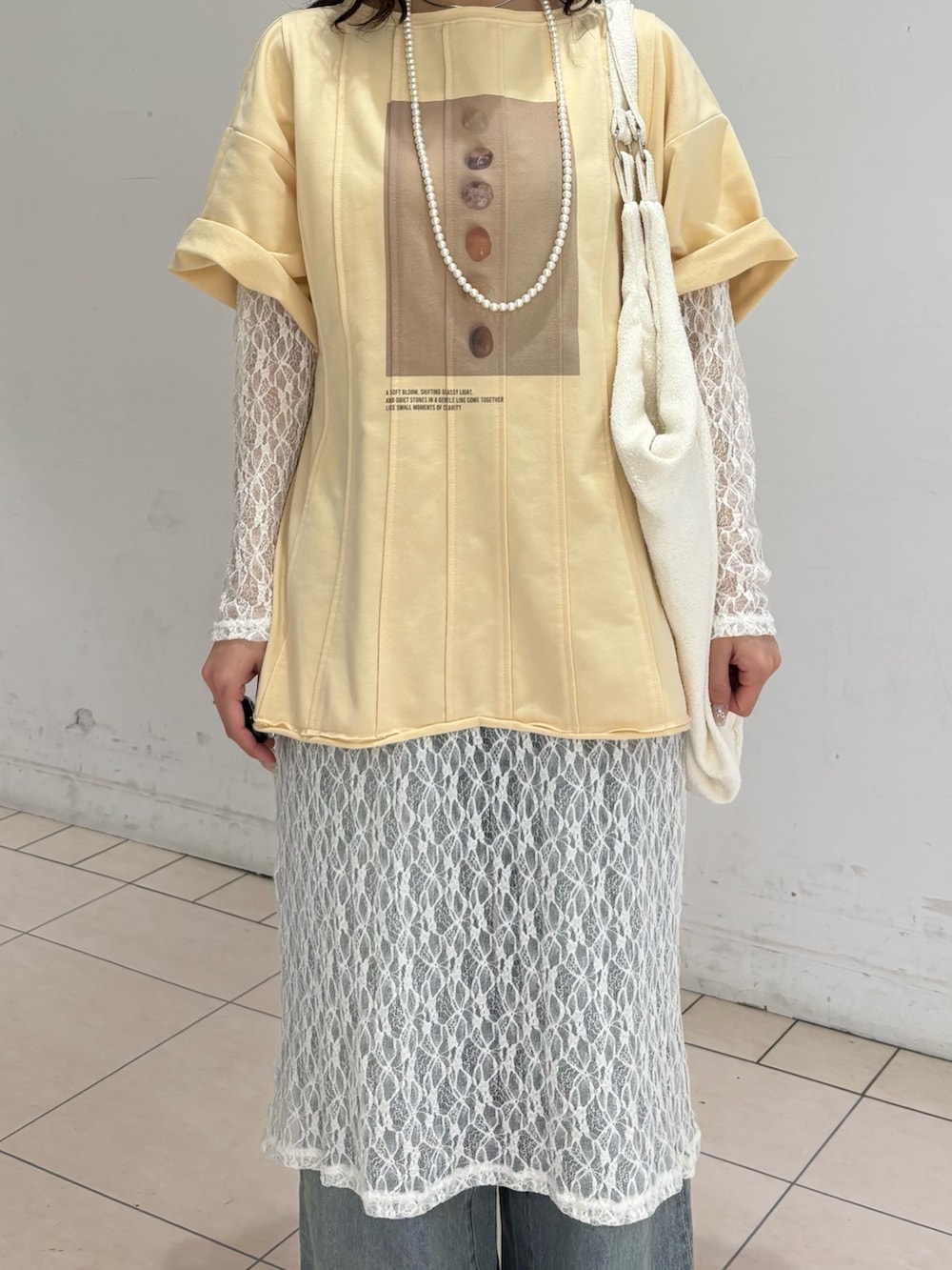 ブルー系のデニムパンツ、ホワイト系のワンピース、イエロー系のTシャツ/カットソーを着用したレディースの春コーディネートの4枚目の写真