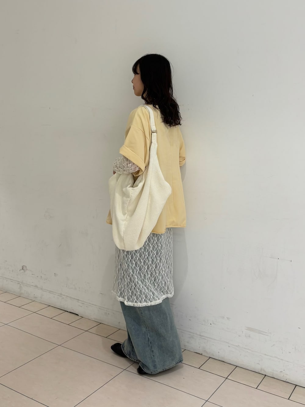 ブルー系のデニムパンツ、ホワイト系のワンピース、イエロー系のTシャツ/カットソーを着用したレディースの春コーディネートの2枚目の写真