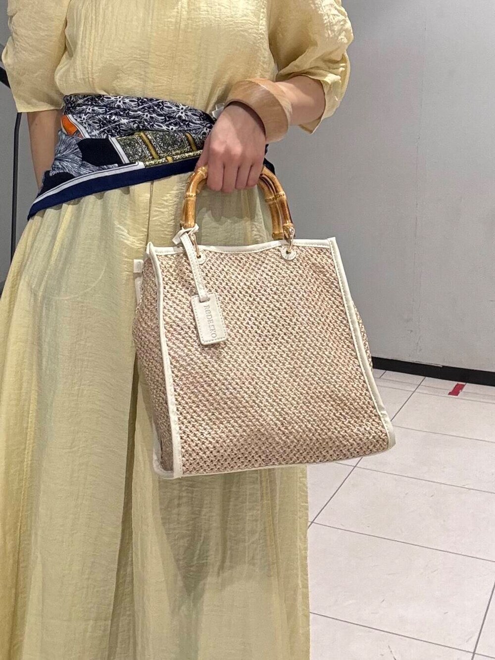 ブルー系のデニムパンツ、イエロー系のその他シューズ、ホワイト系のショルダーバッグを着用したレディースの春コーディネートの5枚目の写真