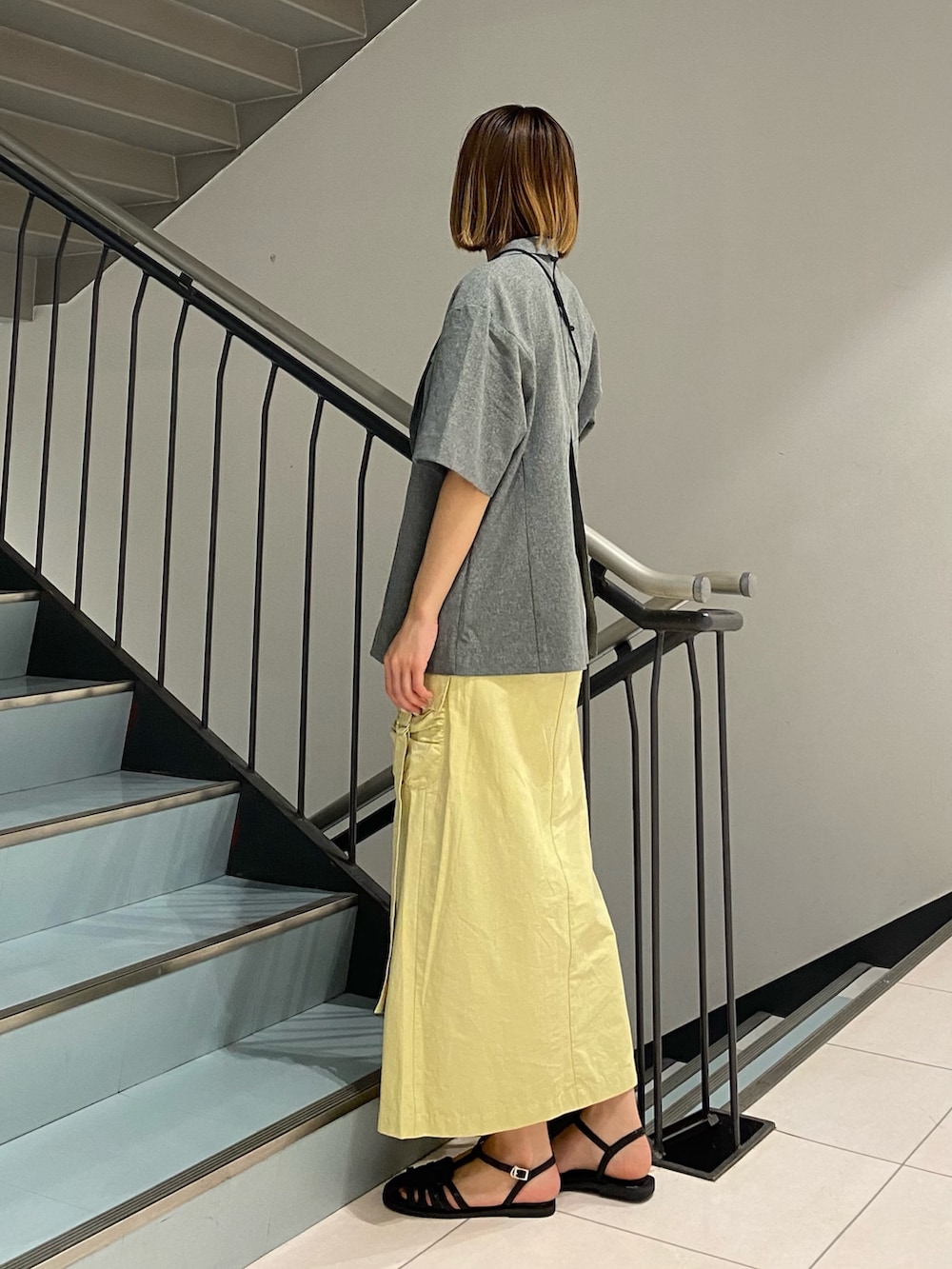 グレー系のその他アウター、イエロー系のスカート、ブラック系のサンダルを着用したレディースの春コーディネートの2枚目の写真