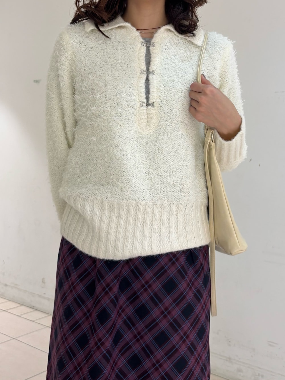 レッド系のスカート、ホワイト系のニット/セーターを着用したレディースの冬コーディネートの2枚目の写真