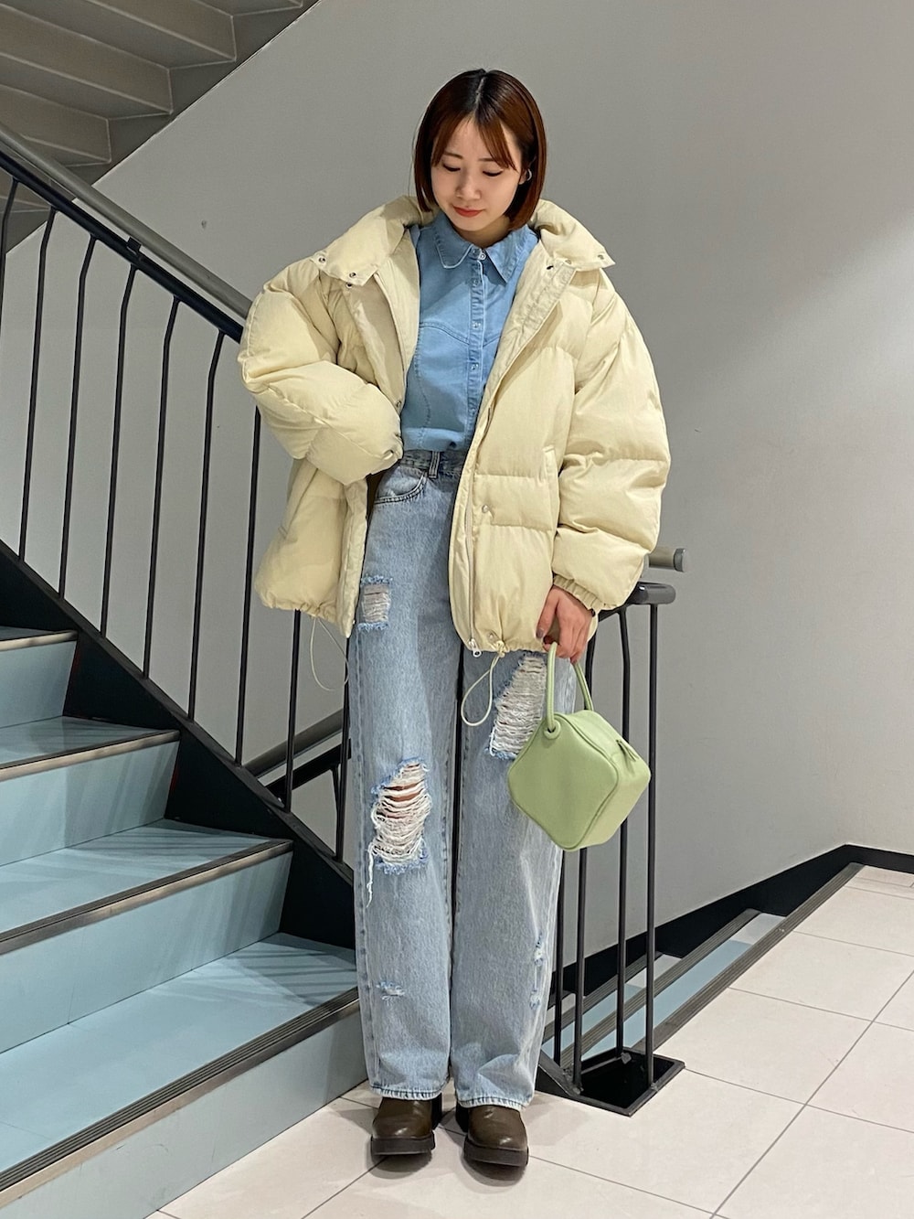 ブルー系のデニムパンツ、グリーン系のハンドバッグ、ブルー系のシャツ/ブラウスを着用したレディースの冬コーディネートの2枚目の写真