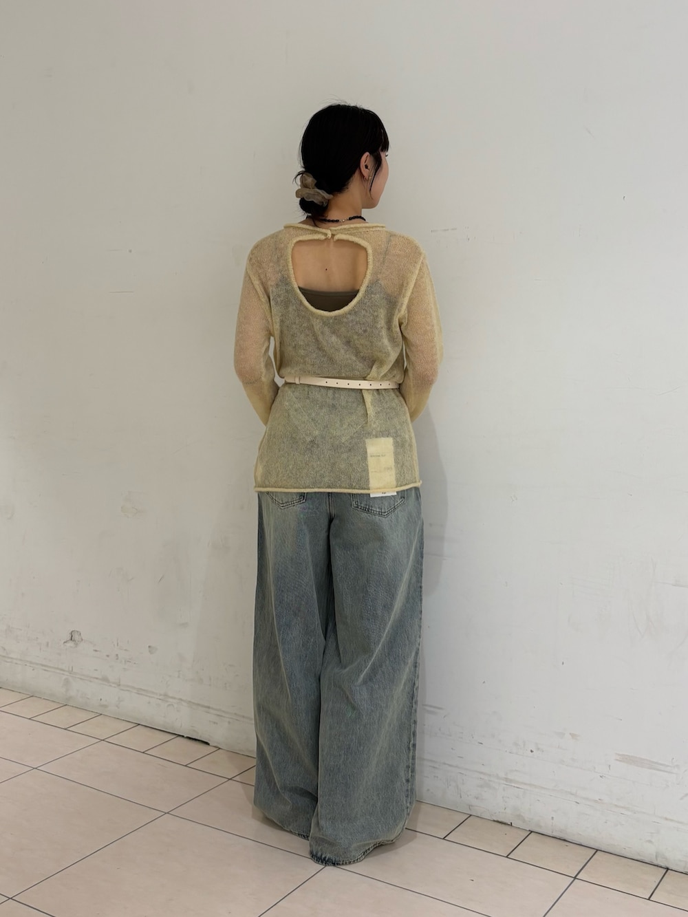 ブルー系のデニムパンツ、イエロー系のニット/セーター、ホワイト系のボディバッグ/ウエストポーチを着用したレディースの冬コーディネートの2枚目の写真