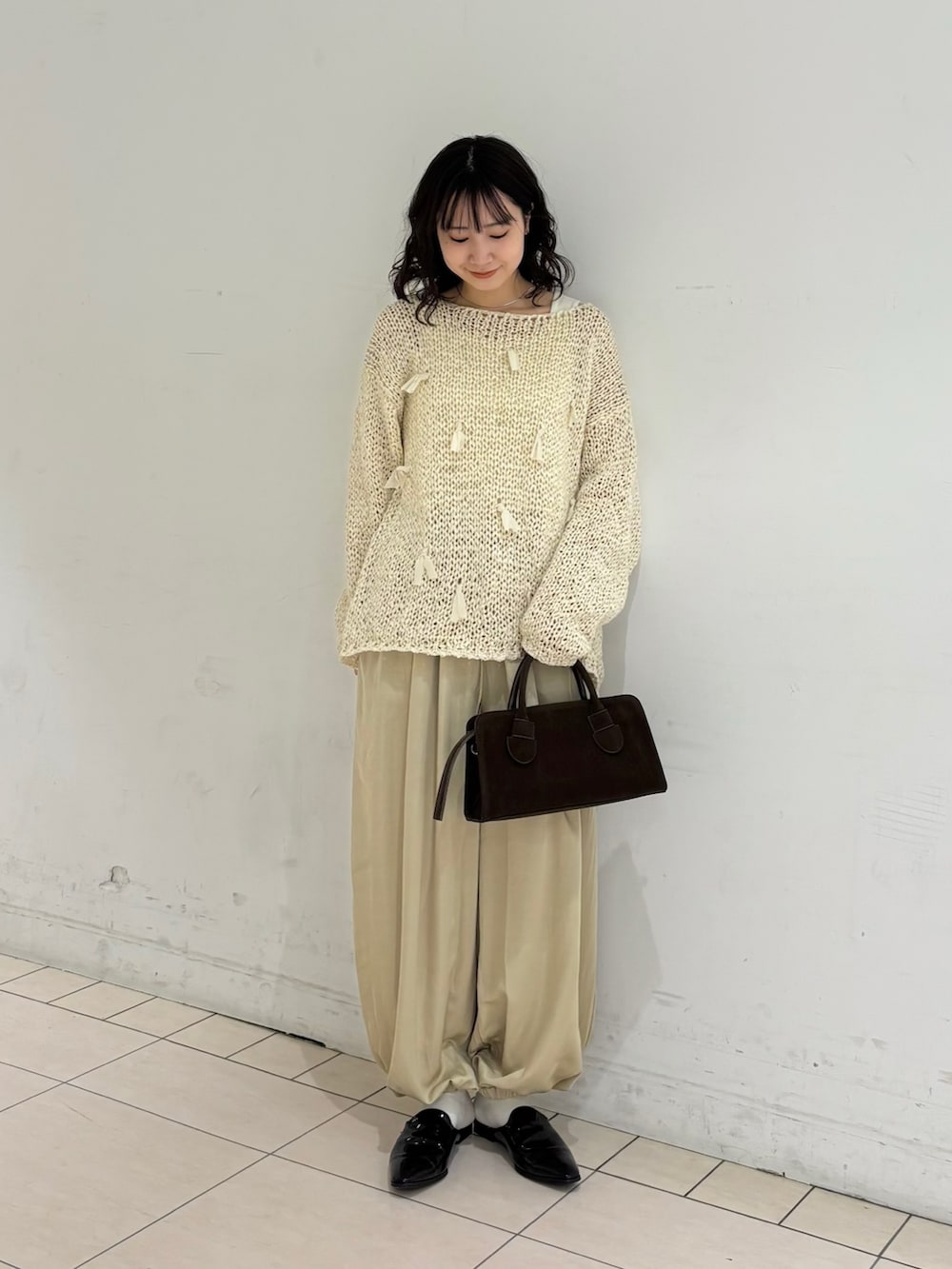 ホワイト系のニット/セーター、ベージュ系のその他パンツ、ブラウン系のボストンバッグを着用したレディースの冬コーディネートの2枚目の写真