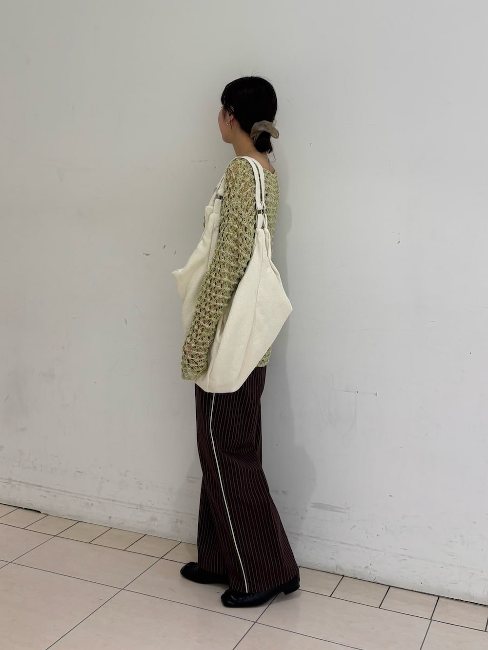 ブラウン系のその他パンツ、グリーン系のニット/セーター、ホワイト系のトートバッグを着用したレディースの春コーディネートの3枚目の写真