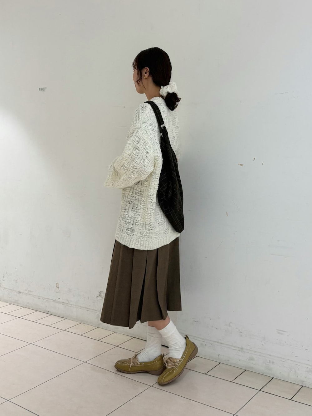 ブラウン系のスカート、ホワイト系のニット/セーター、ブラウン系のトートバッグを着用したレディースの冬コーディネートの3枚目の写真