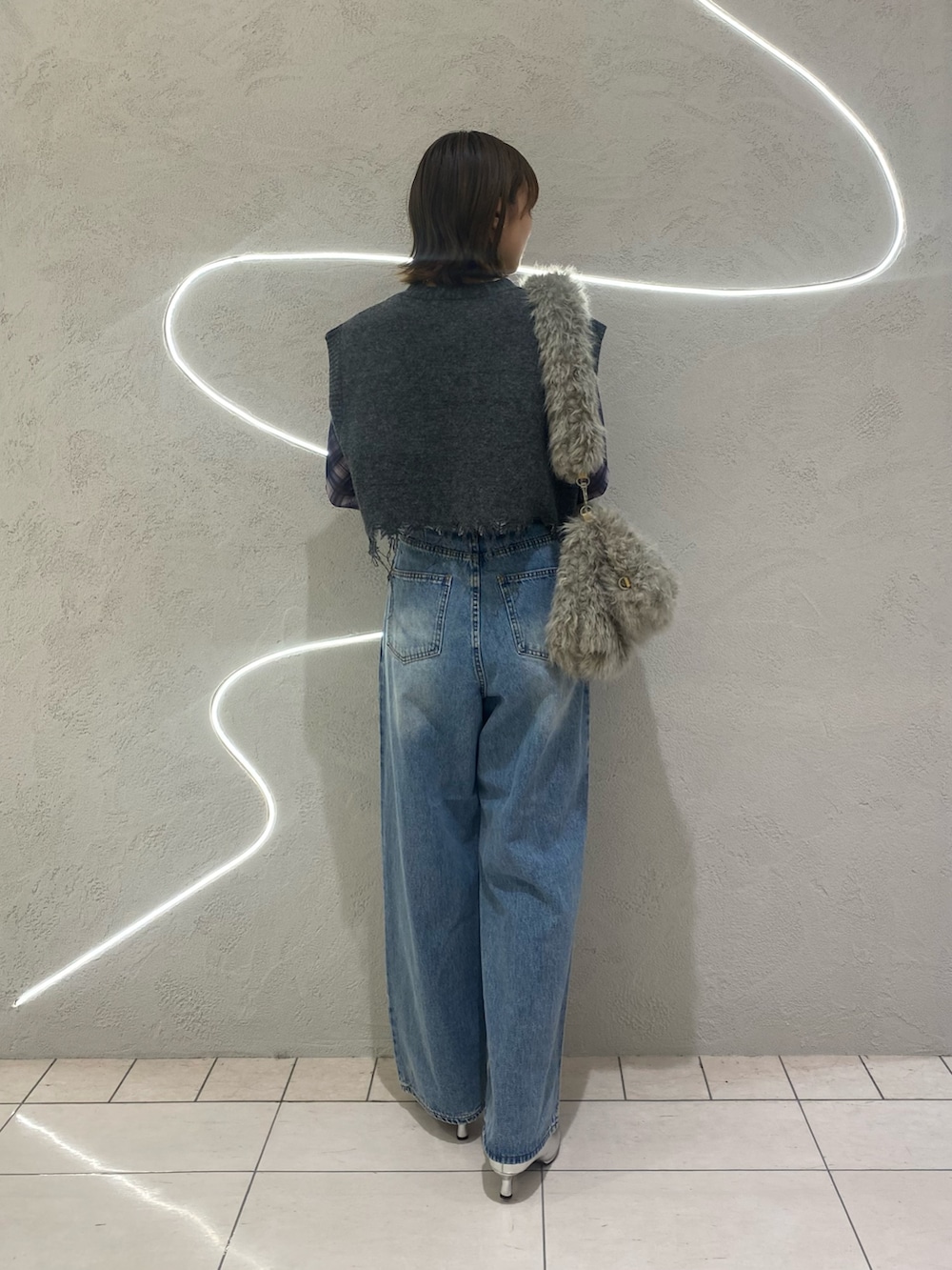 ブルー系のデニムパンツ、グレー系のベスト、ブルー系のTシャツ/カットソーを着用したレディースの秋コーディネートの3枚目の写真