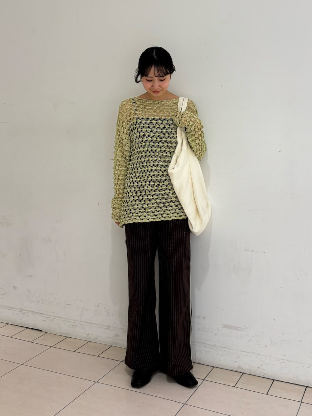 ブラウン系のその他パンツ、グリーン系のニット/セーター、ホワイト系のトートバッグを着用したレディースの春コーディネートの2枚目の写真