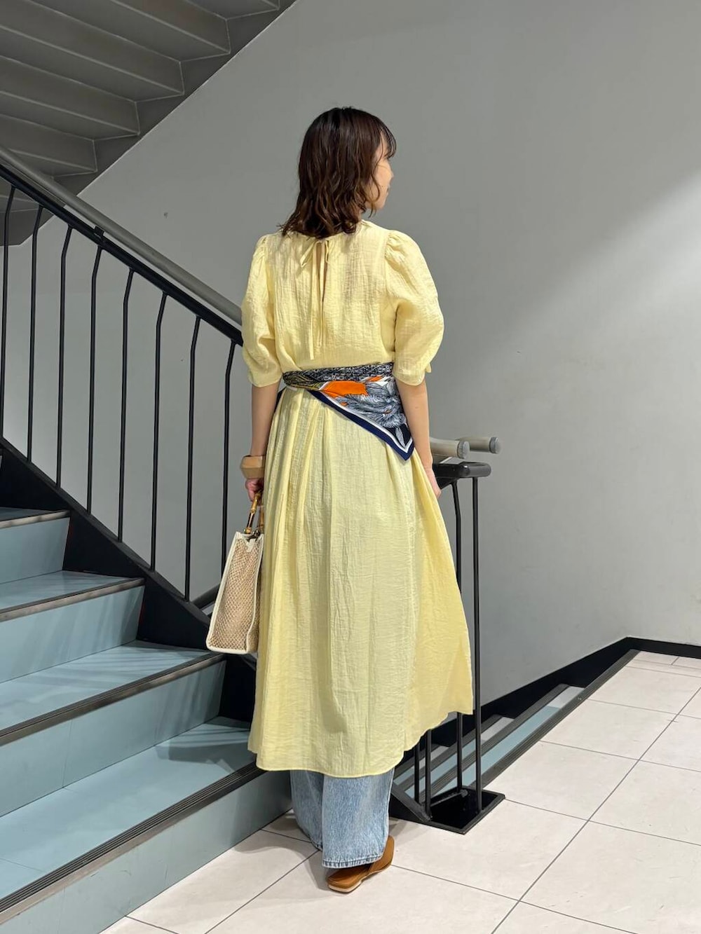 ブルー系のデニムパンツ、イエロー系のその他シューズ、ホワイト系のショルダーバッグを着用したレディースの春コーディネートの4枚目の写真