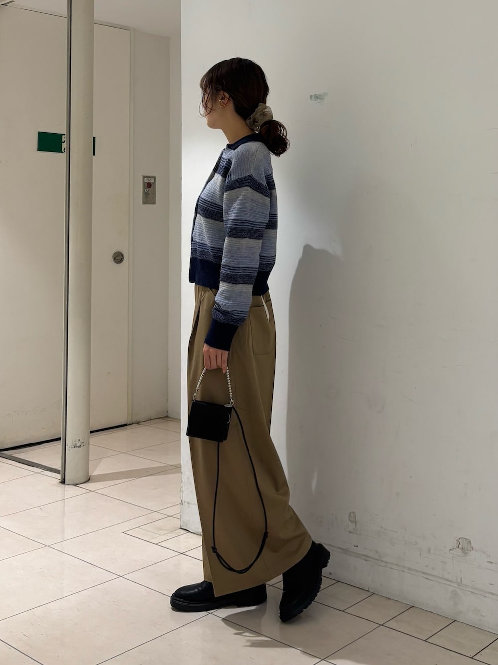 ベージュ系のその他パンツ、ブルー系のカーディガン/ボレロ、ブラック系の財布を着用したレディースの秋コーディネートの2枚目の写真