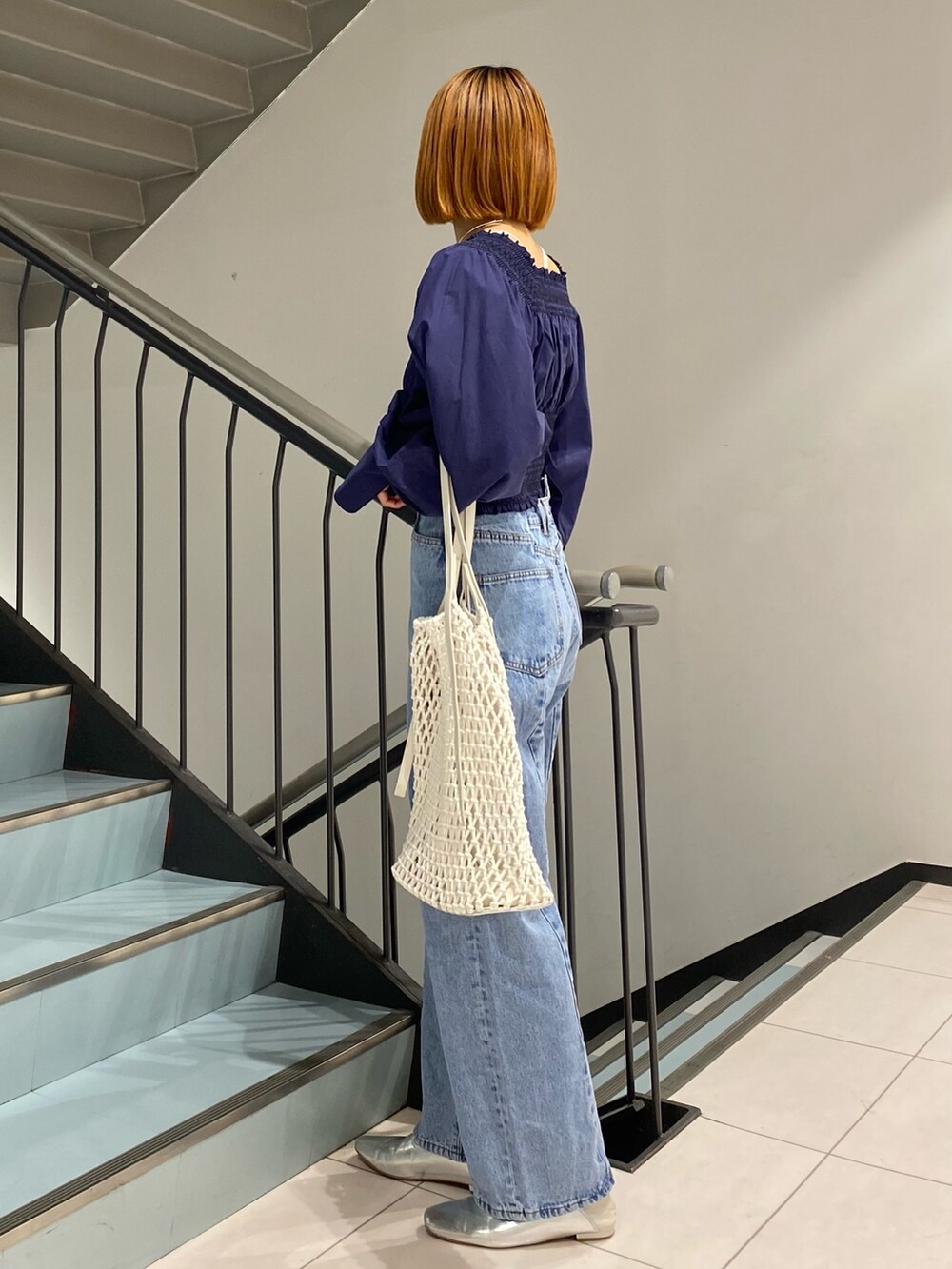 ブルー系のデニムパンツ、ホワイト系のハンドバッグ、ブルー系のシャツ/ブラウスを着用したレディースの春コーディネートの2枚目の写真