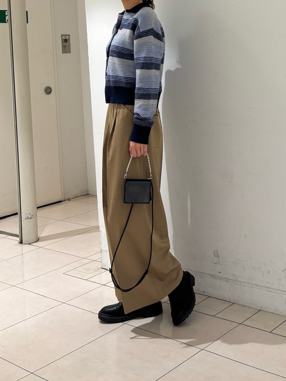 ベージュ系のその他パンツ、ブルー系のカーディガン/ボレロ、ブラック系の財布を着用したレディースの秋コーディネートの4枚目の写真