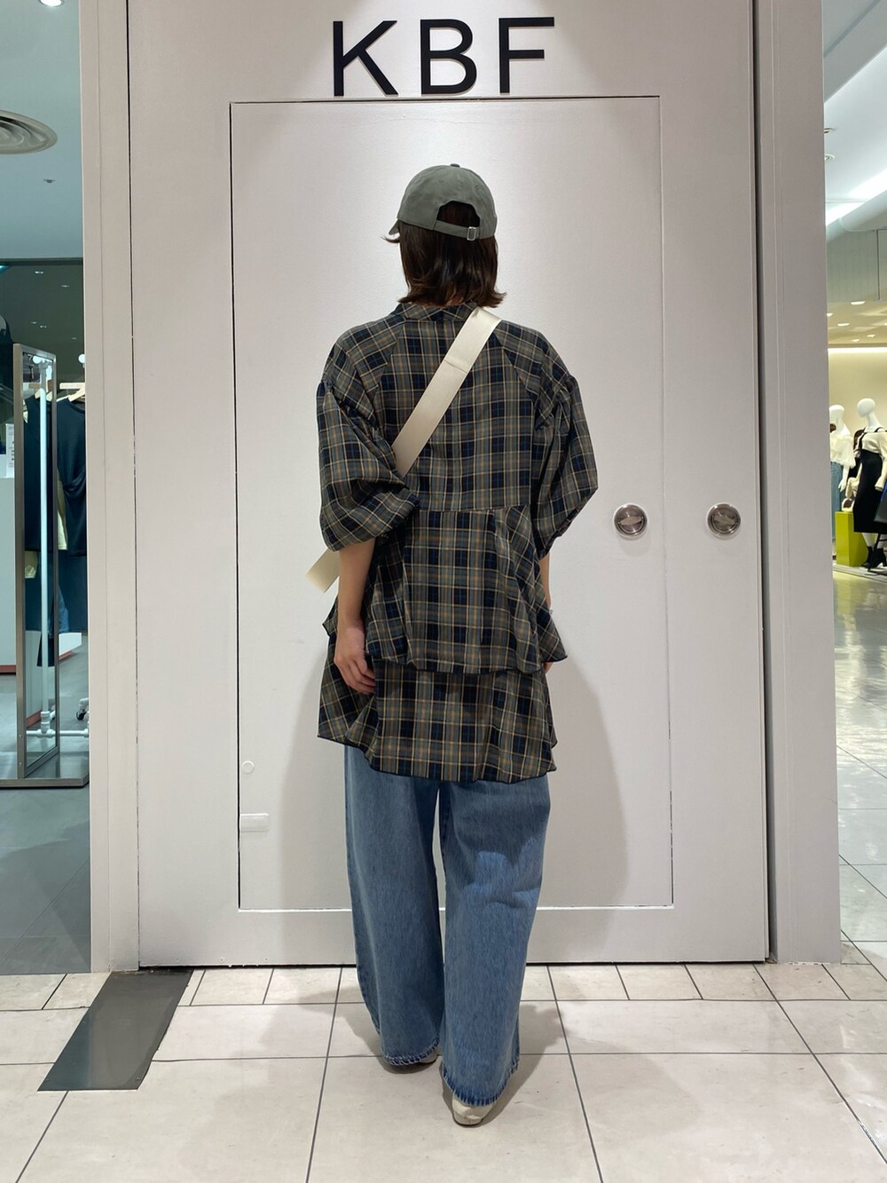 ブルー系のデニムパンツ、ブラック系のワンピース、ホワイト系のショルダーバッグを着用したレディースの秋コーディネートの2枚目の写真