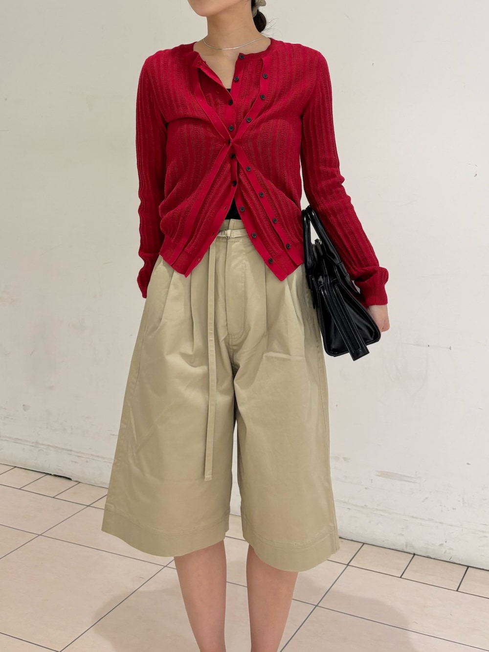 ベージュ系のその他パンツ、レッド系のニット/セーター、ブラック系のボストンバッグを着用したレディースの春コーディネートの3枚目の写真