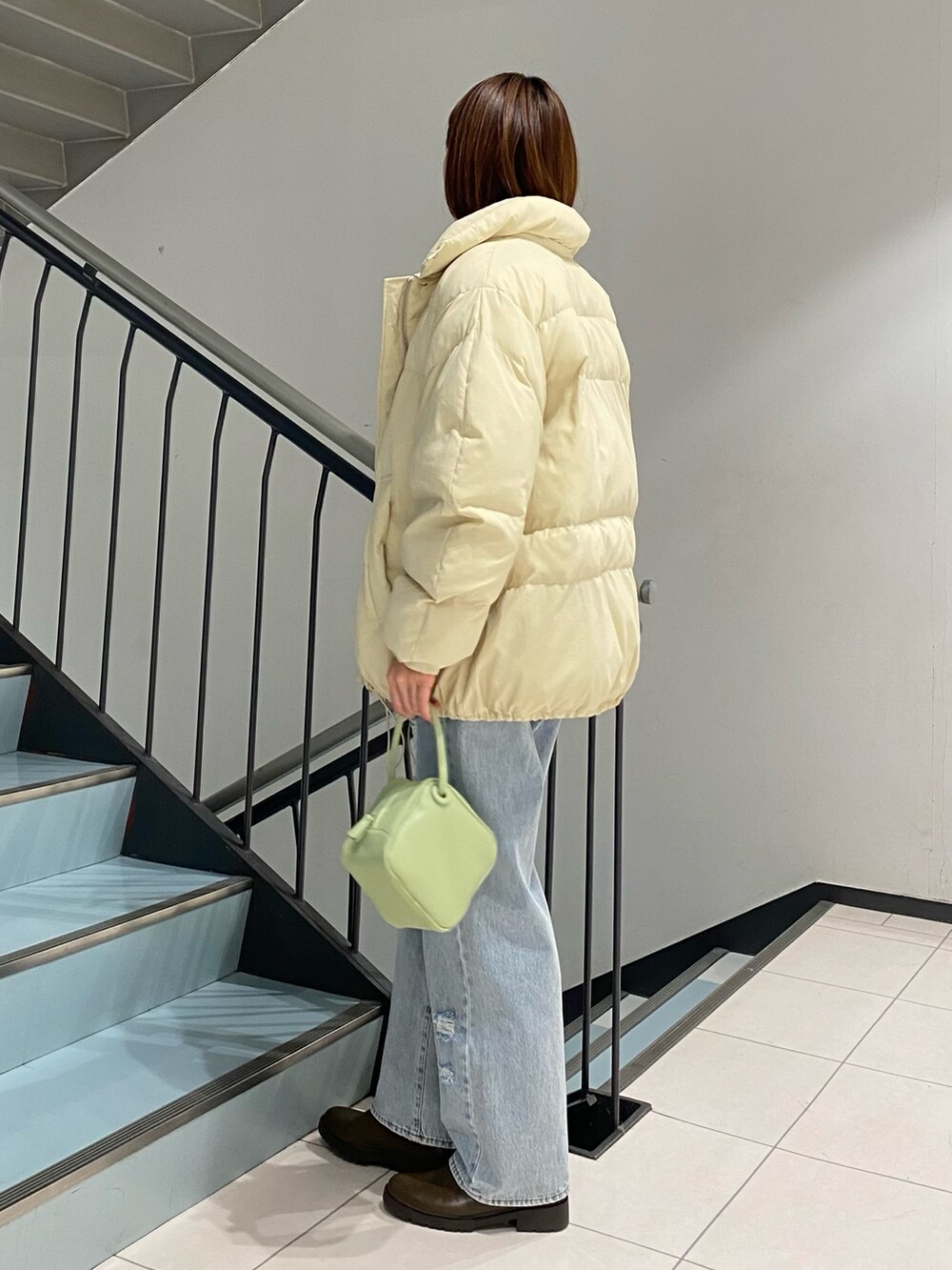 ブルー系のデニムパンツ、グリーン系のハンドバッグ、ブルー系のシャツ/ブラウスを着用したレディースの冬コーディネートの3枚目の写真