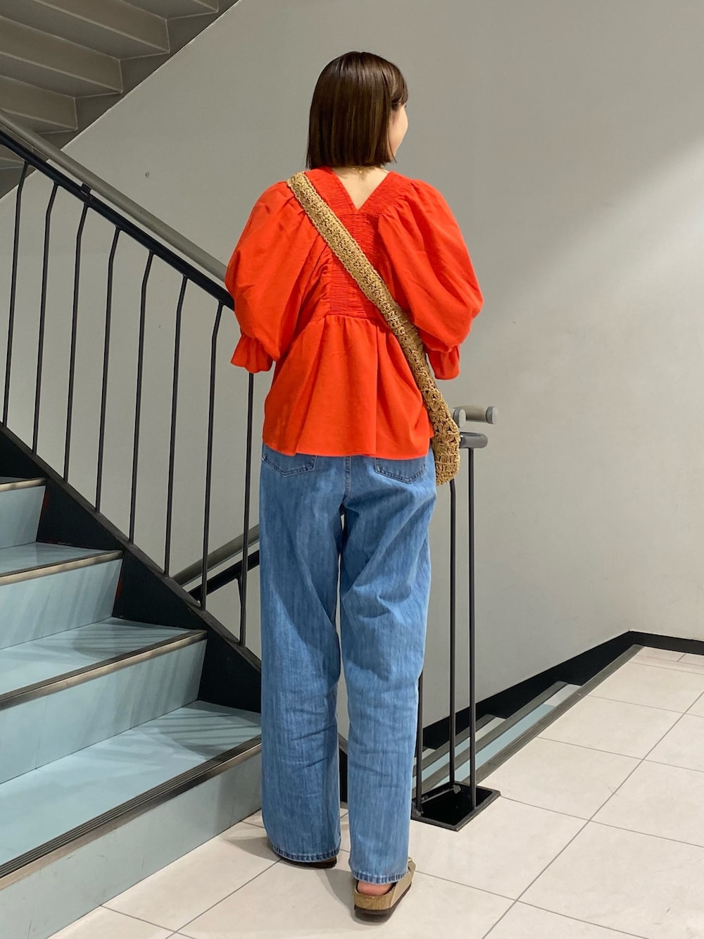 ブルー系のデニムパンツ、レッド系のシャツ/ブラウス、イエロー系のトートバッグを着用したレディースの春コーディネートの3枚目の写真