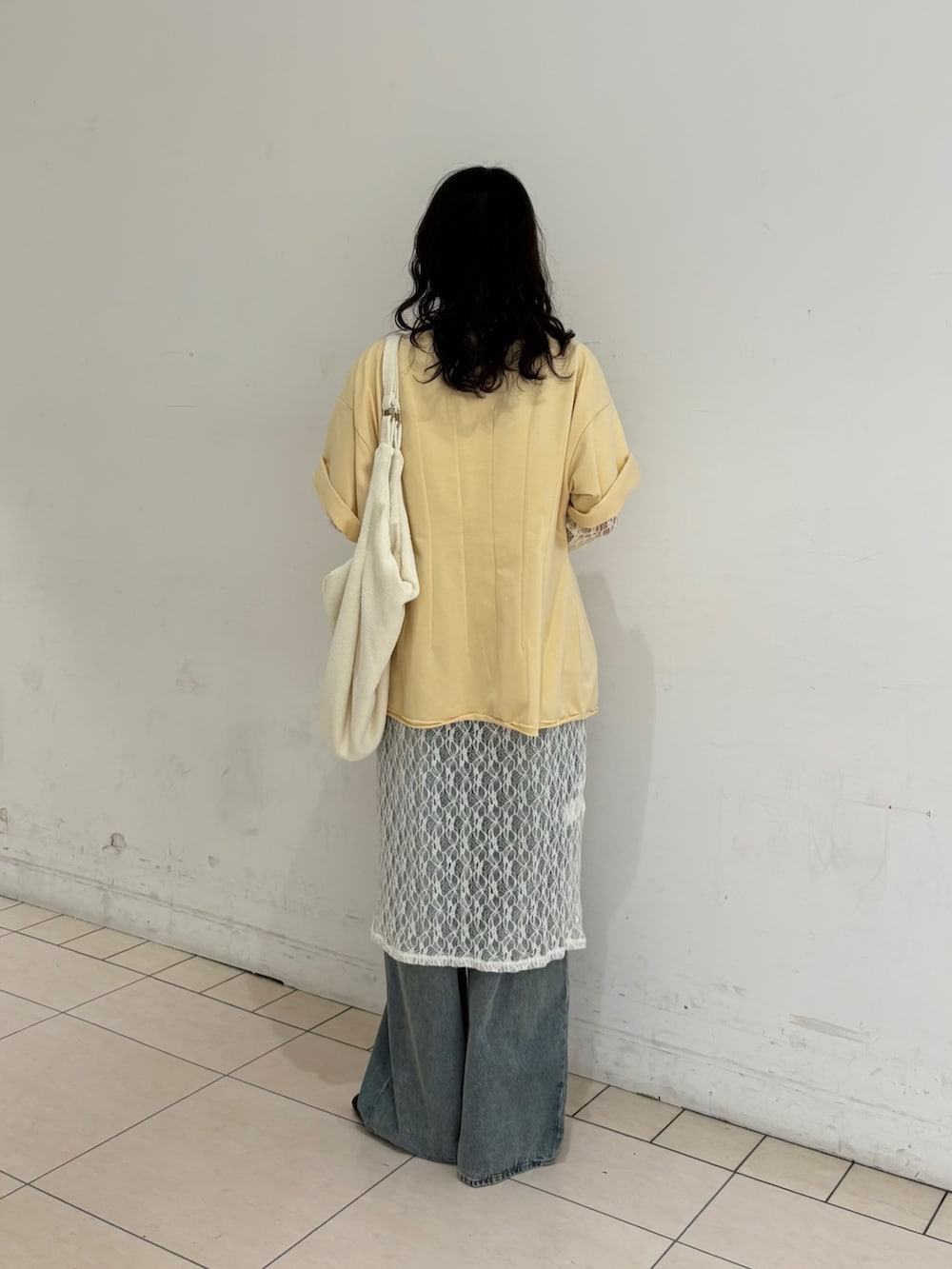 ブルー系のデニムパンツ、ホワイト系のワンピース、イエロー系のTシャツ/カットソーを着用したレディースの春コーディネートの3枚目の写真