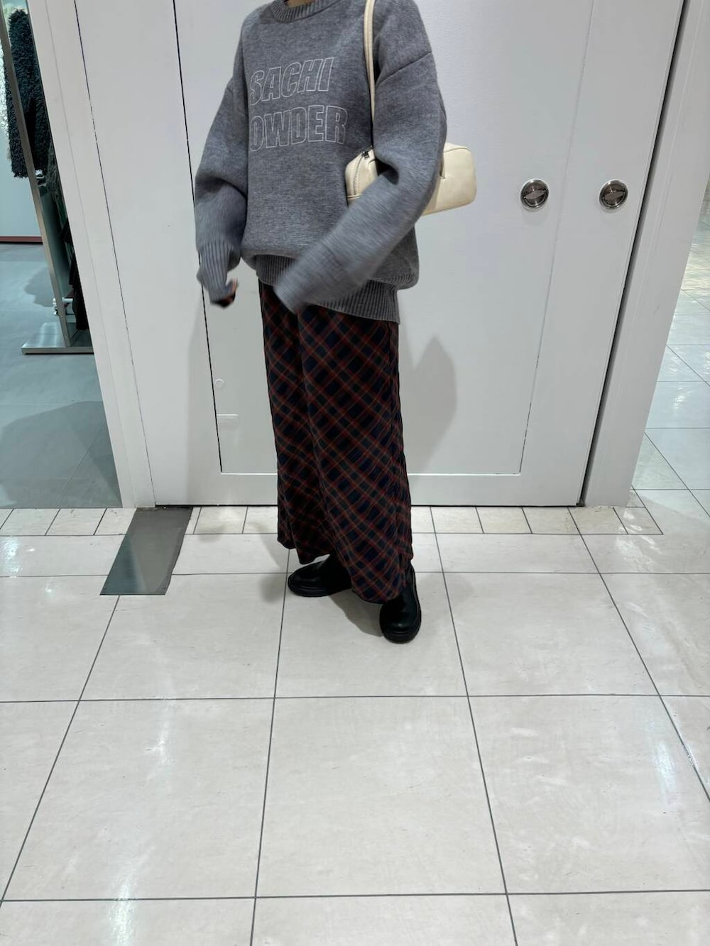 グレー系のニット/セーター、ホワイト系のショルダーバッグ、ブルー系のスカートを着用したレディースの秋コーディネートの2枚目の写真