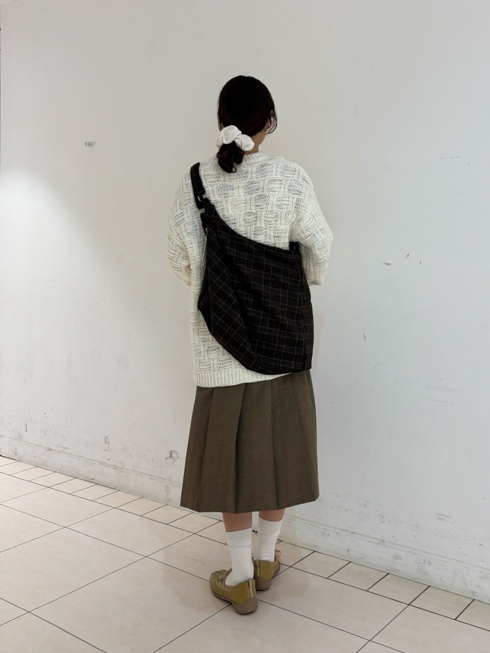 ブラウン系のスカート、ホワイト系のニット/セーター、ブラウン系のトートバッグを着用したレディースの冬コーディネートの4枚目の写真