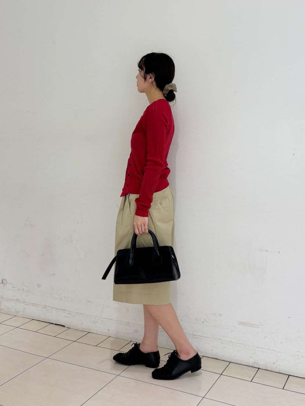 ベージュ系のその他パンツ、レッド系のニット/セーター、ブラック系のボストンバッグを着用したレディースの春コーディネートの2枚目の写真