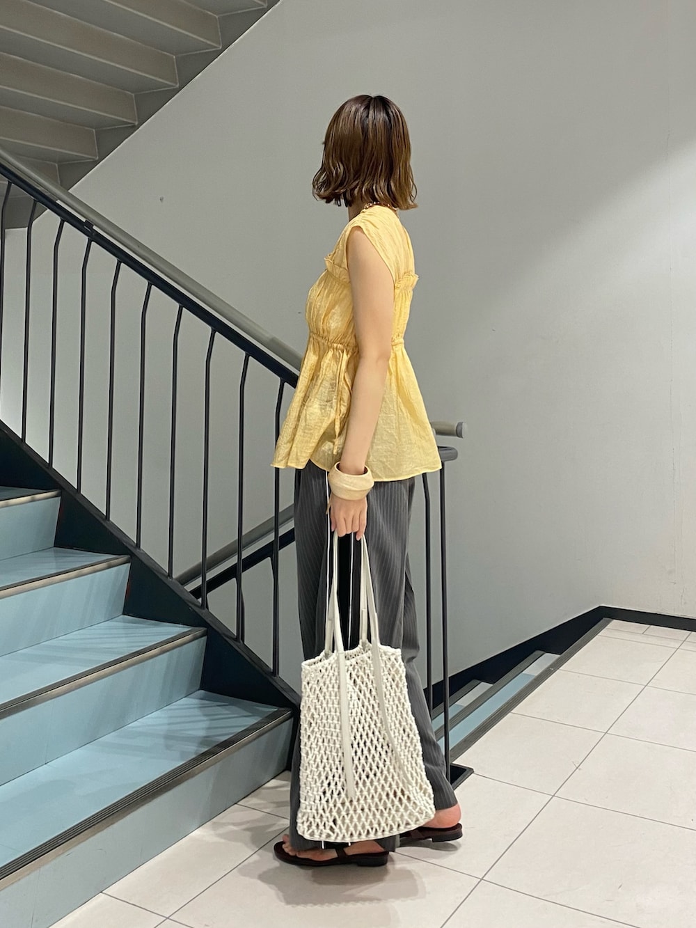 オレンジ系のシャツ/ブラウス、グレー系のその他パンツ、ホワイト系のハンドバッグを着用したレディースの夏コーディネートの2枚目の写真