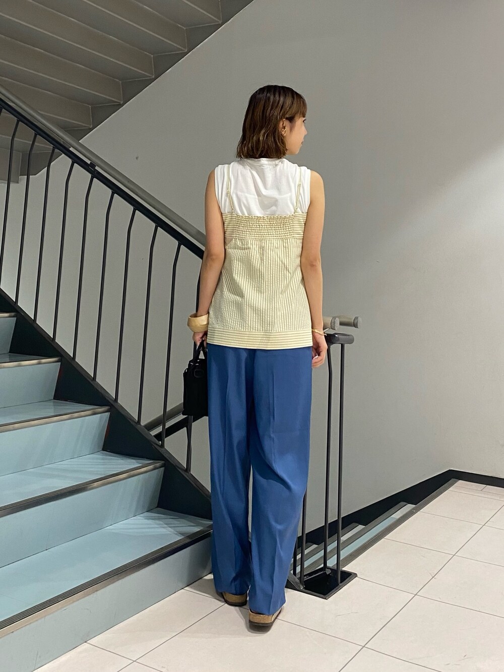 ブルー系のスラックス、ブラック系のシャツ/ブラウス、ブラック系のショルダーバッグを着用したレディースの夏コーディネートの2枚目の写真