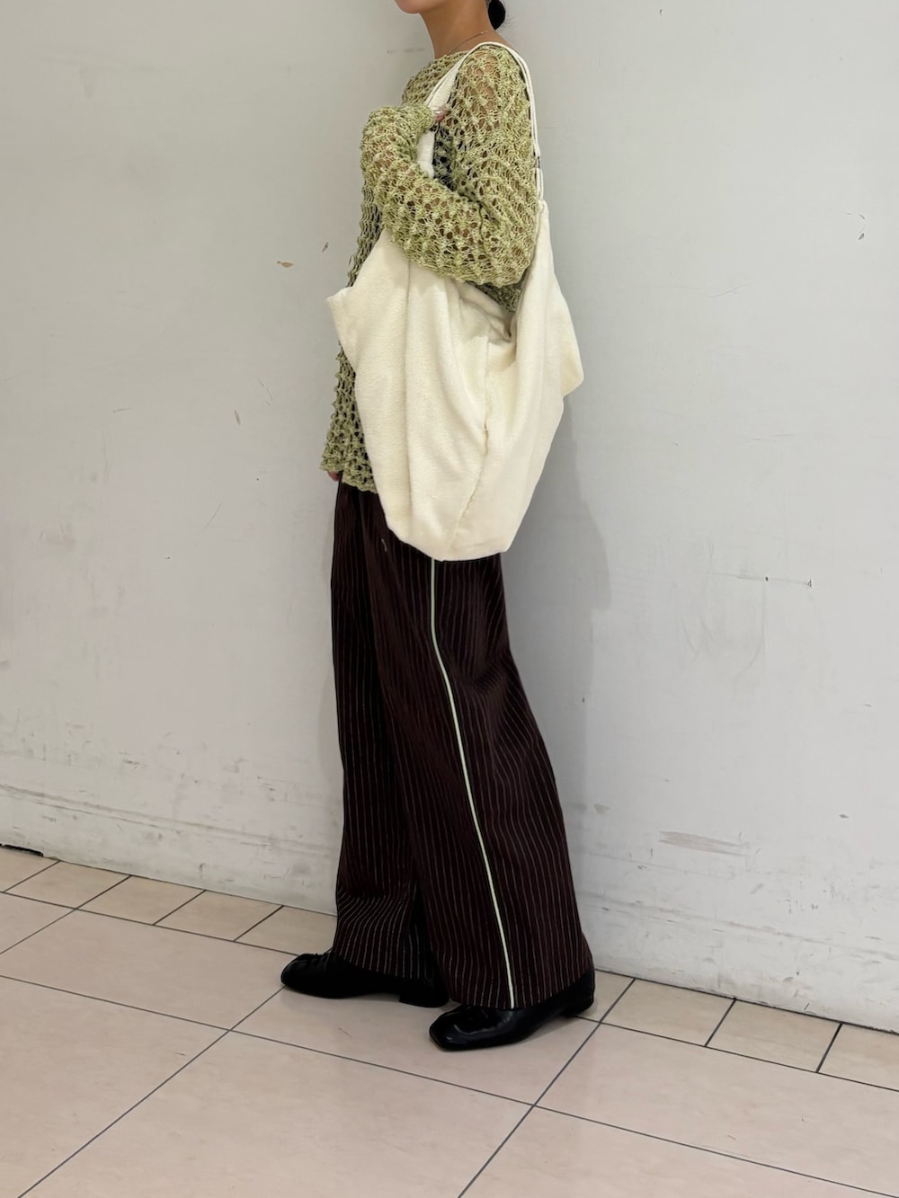 ブラウン系のその他パンツ、グリーン系のニット/セーター、ホワイト系のトートバッグを着用したレディースの春コーディネートの4枚目の写真