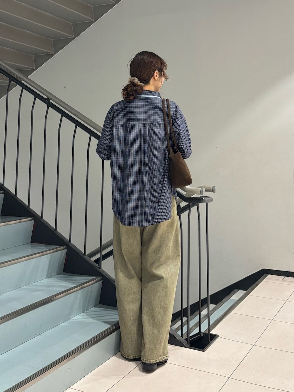 グリーン系のデニムパンツ、ブルー系のシャツ/ブラウス、ブラウン系のボストンバッグを着用したレディースの秋コーディネートの3枚目の写真