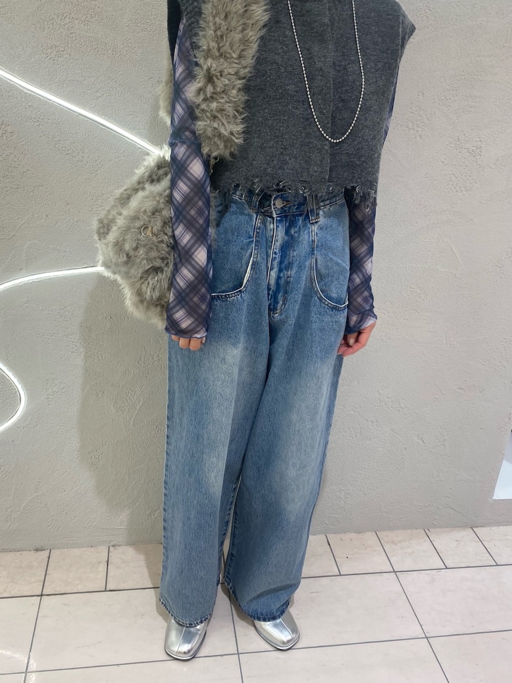 ブルー系のデニムパンツ、グレー系のベスト、ブルー系のTシャツ/カットソーを着用したレディースの秋コーディネートの2枚目の写真