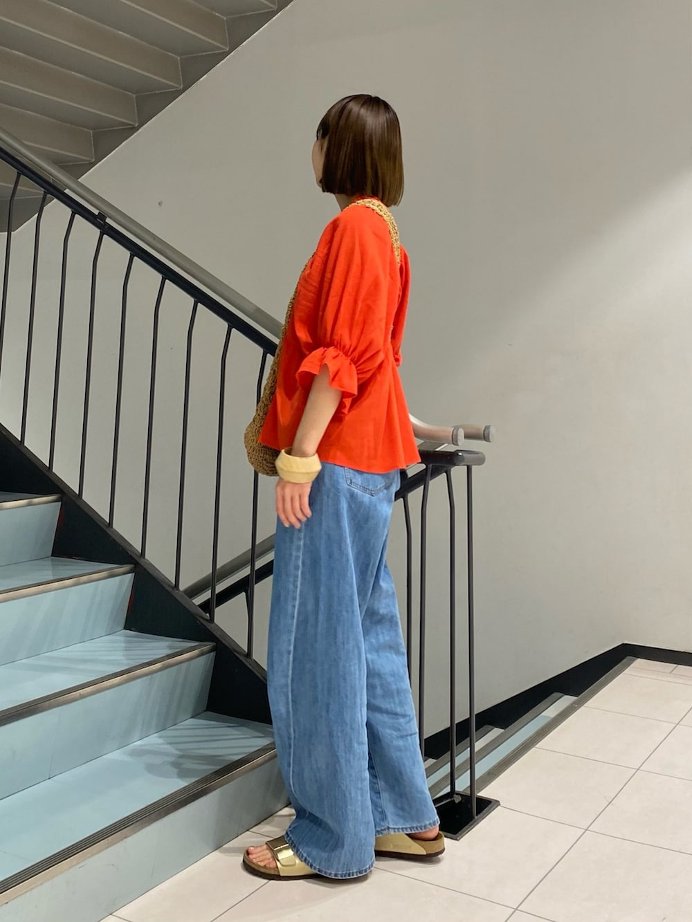 ブルー系のデニムパンツ、レッド系のシャツ/ブラウス、イエロー系のトートバッグを着用したレディースの春コーディネートの2枚目の写真