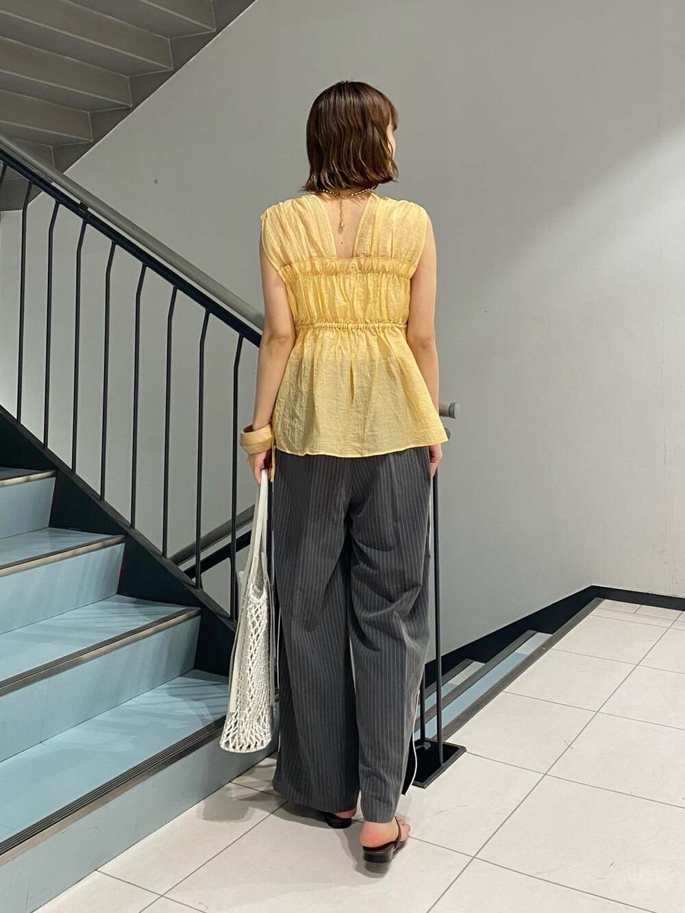 オレンジ系のシャツ/ブラウス、グレー系のその他パンツ、ホワイト系のハンドバッグを着用したレディースの夏コーディネートの3枚目の写真