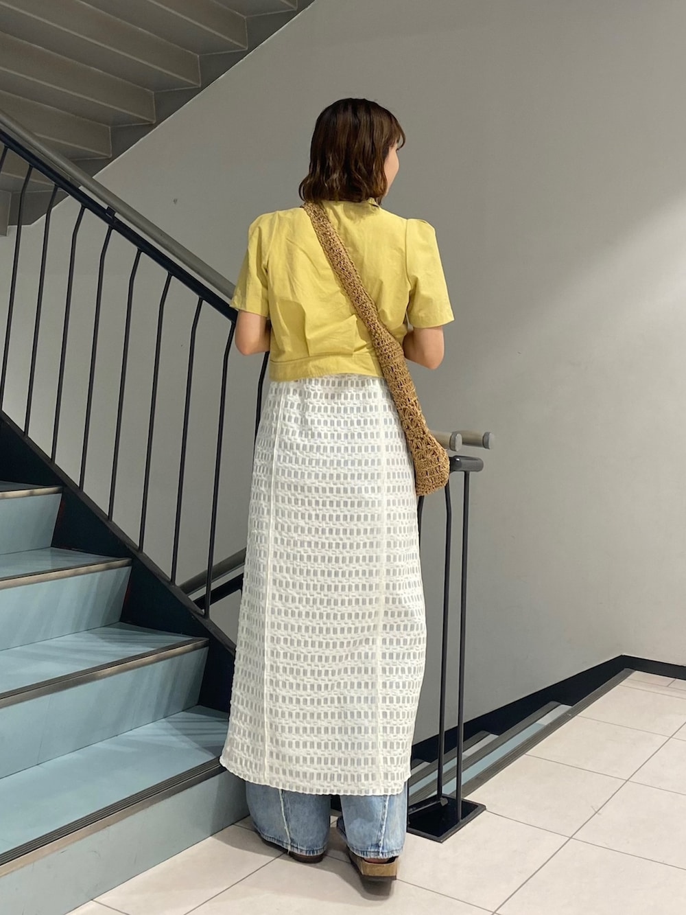 ホワイト系のワンピース、ブルー系のデニムパンツ、イエロー系のトートバッグを着用したレディースの夏コーディネートの3枚目の写真