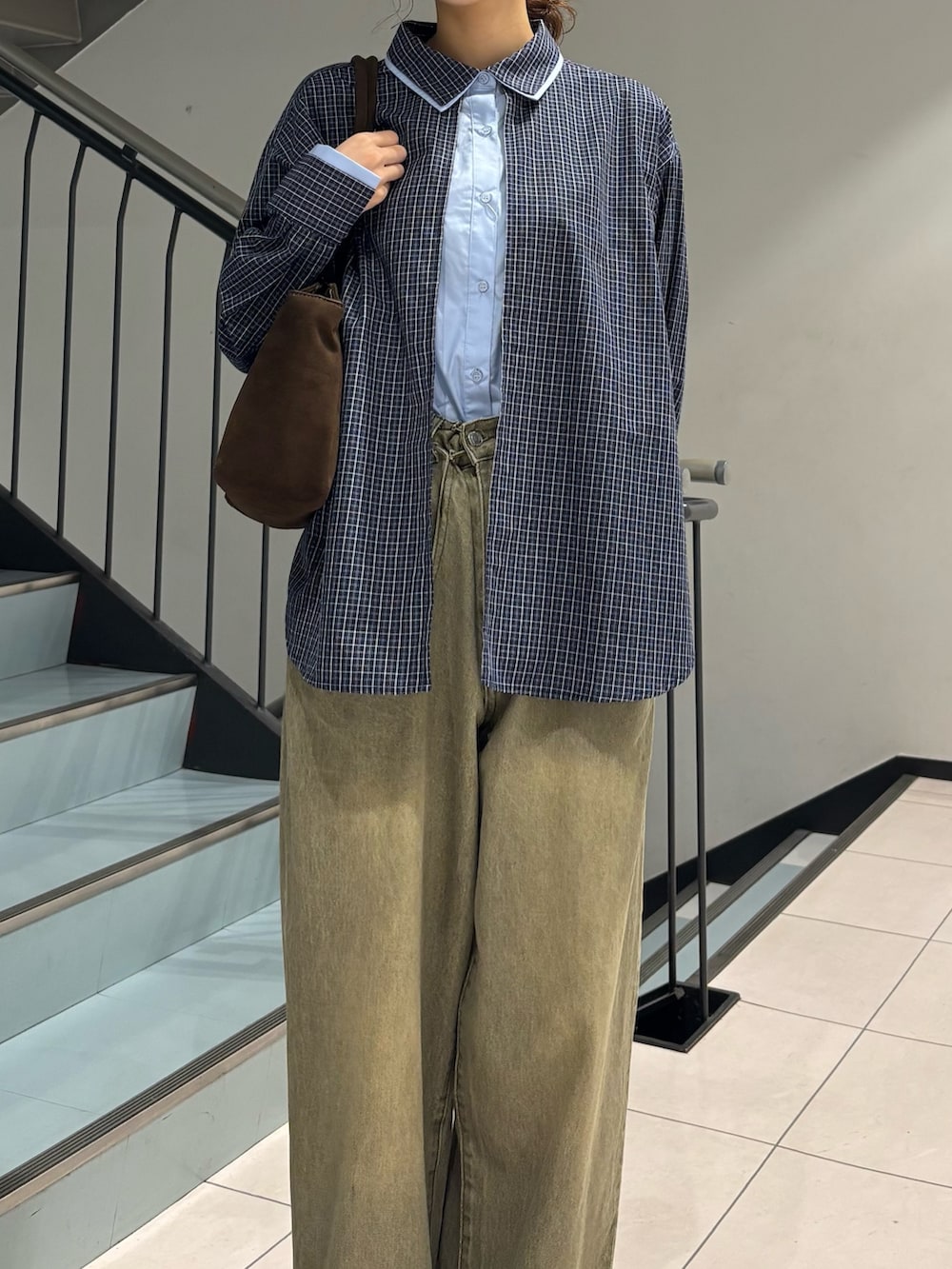 グリーン系のデニムパンツ、ブルー系のシャツ/ブラウス、ブラウン系のボストンバッグを着用したレディースの秋コーディネートの4枚目の写真